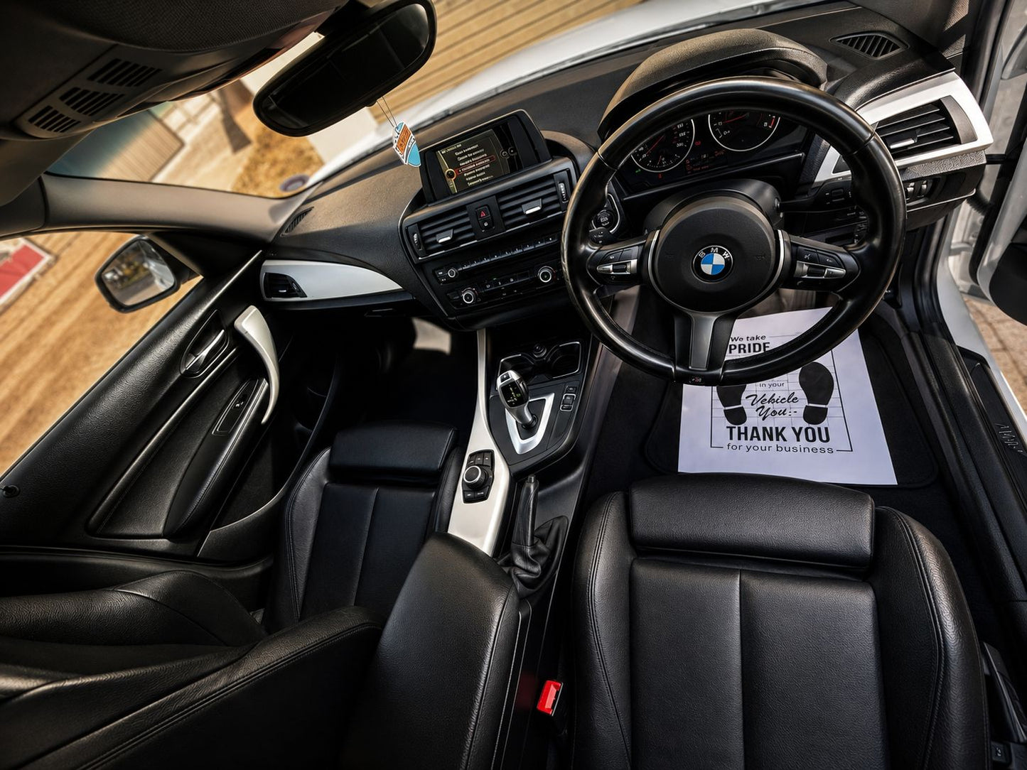 Car interior with a steering wheel and dashboard, featuring a 'Thank You' card.