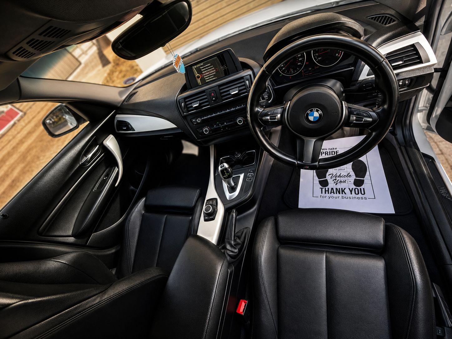 Car interior with a steering wheel and dashboard, featuring a 'Thank You' card.