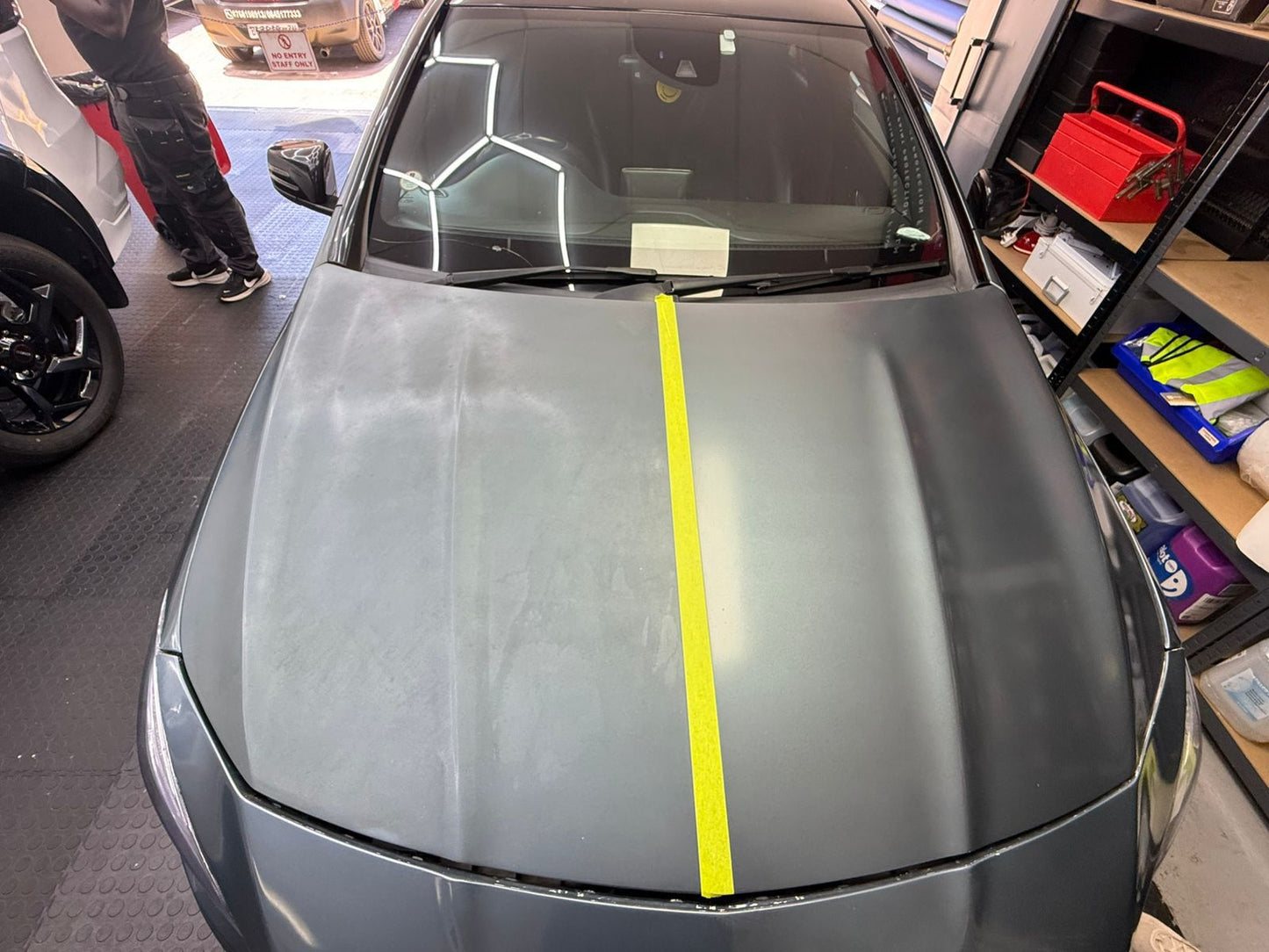 Car hood with a yellow stripe in a garage setting