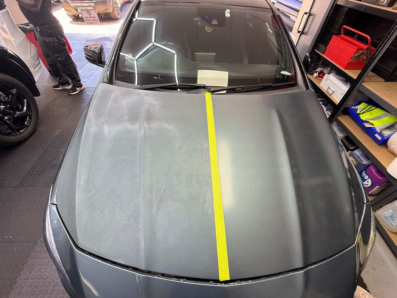 Car hood with a yellow stripe in a garage setting