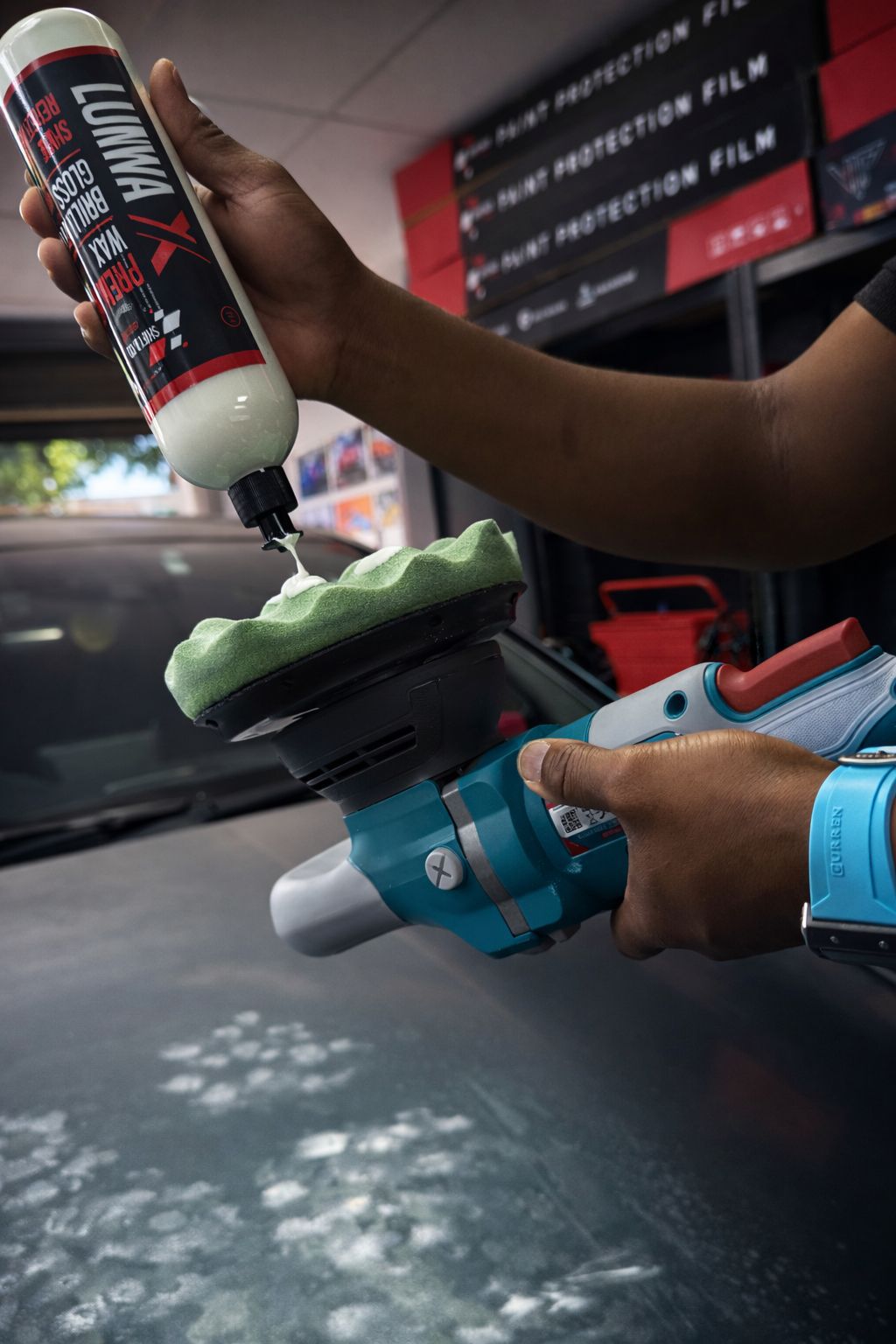 Person using a car detailing tool with a bottle of liquid in a garage setting