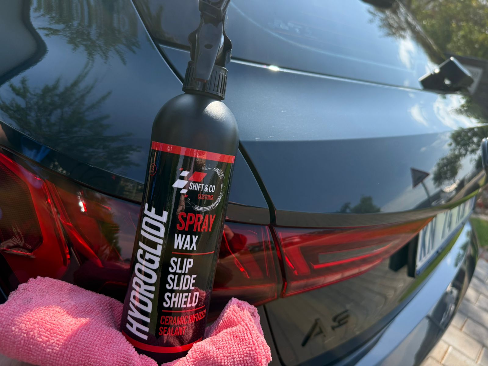 Spray wax bottle with pink towel on car surface