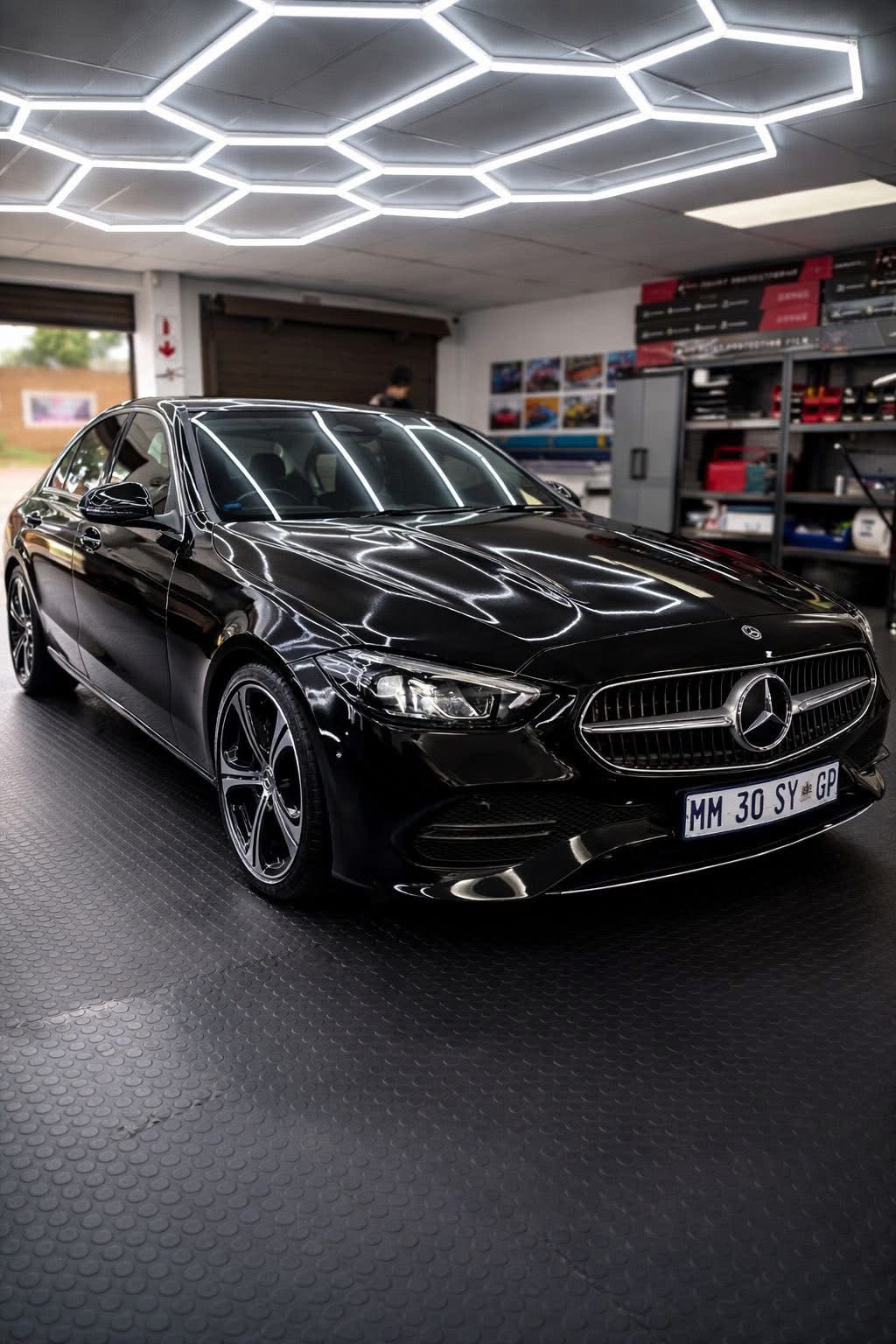 Black Mercedes-Benz car in a showroom with geometric ceiling lights
