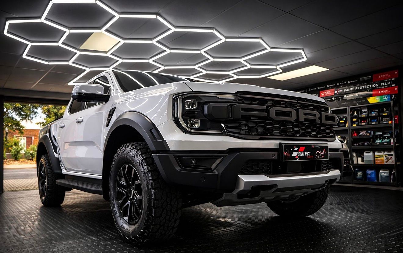 White Ford truck in a showroom with a honeycomb pattern overlay.