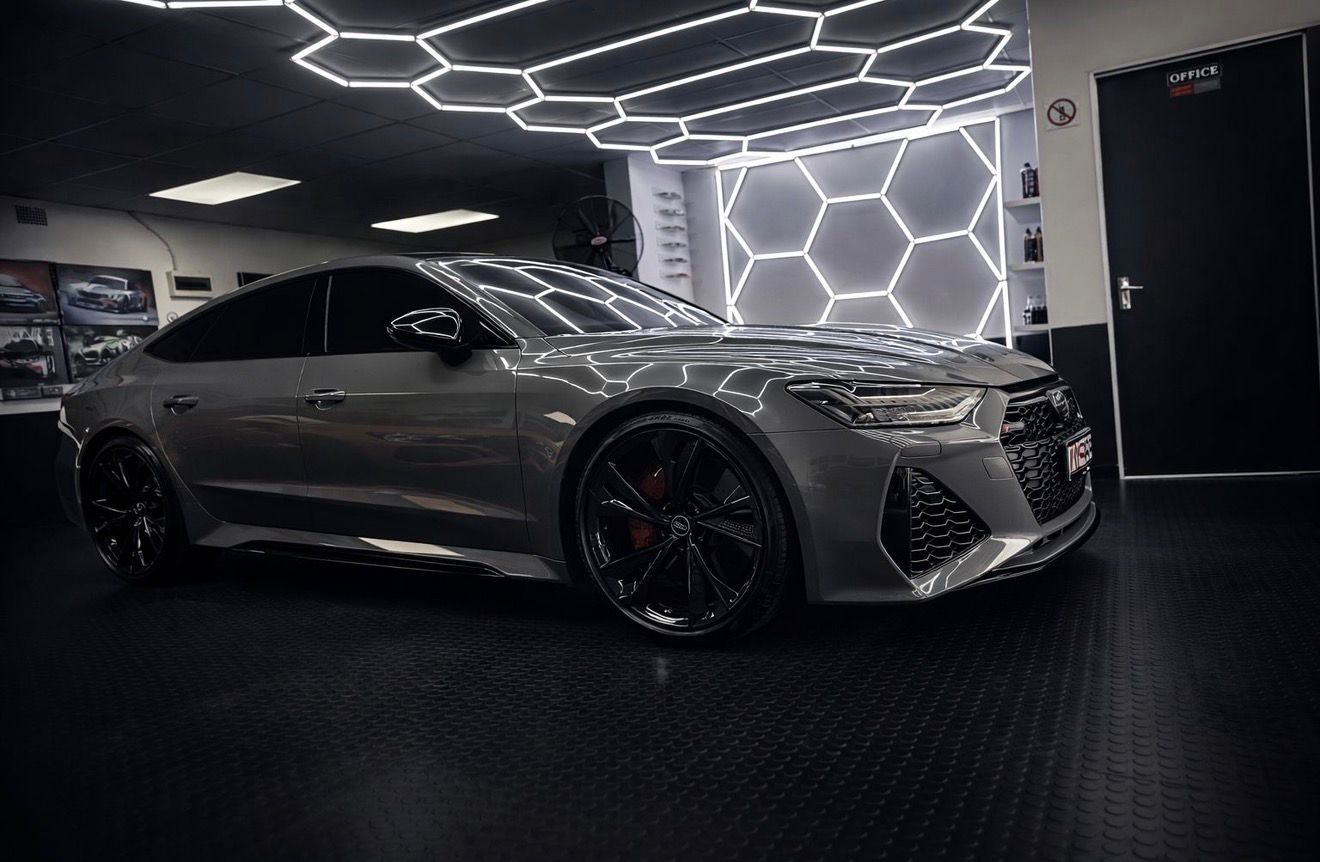 Silver Audi car in a showroom with geometric light design on the ceiling.